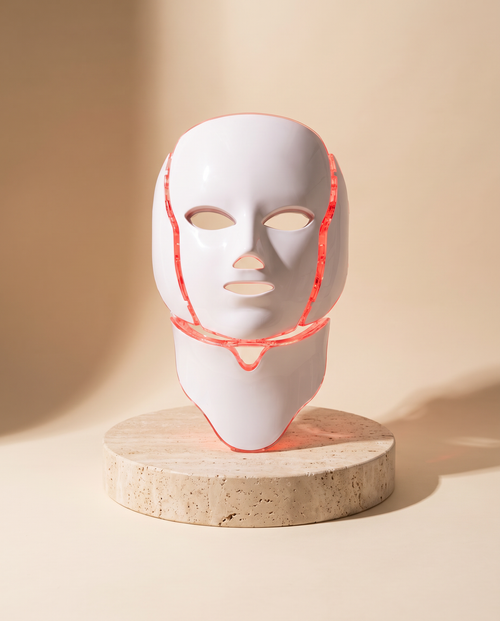Photon LED light therapy mask with neck panel on a travertine pedestal, red light mode