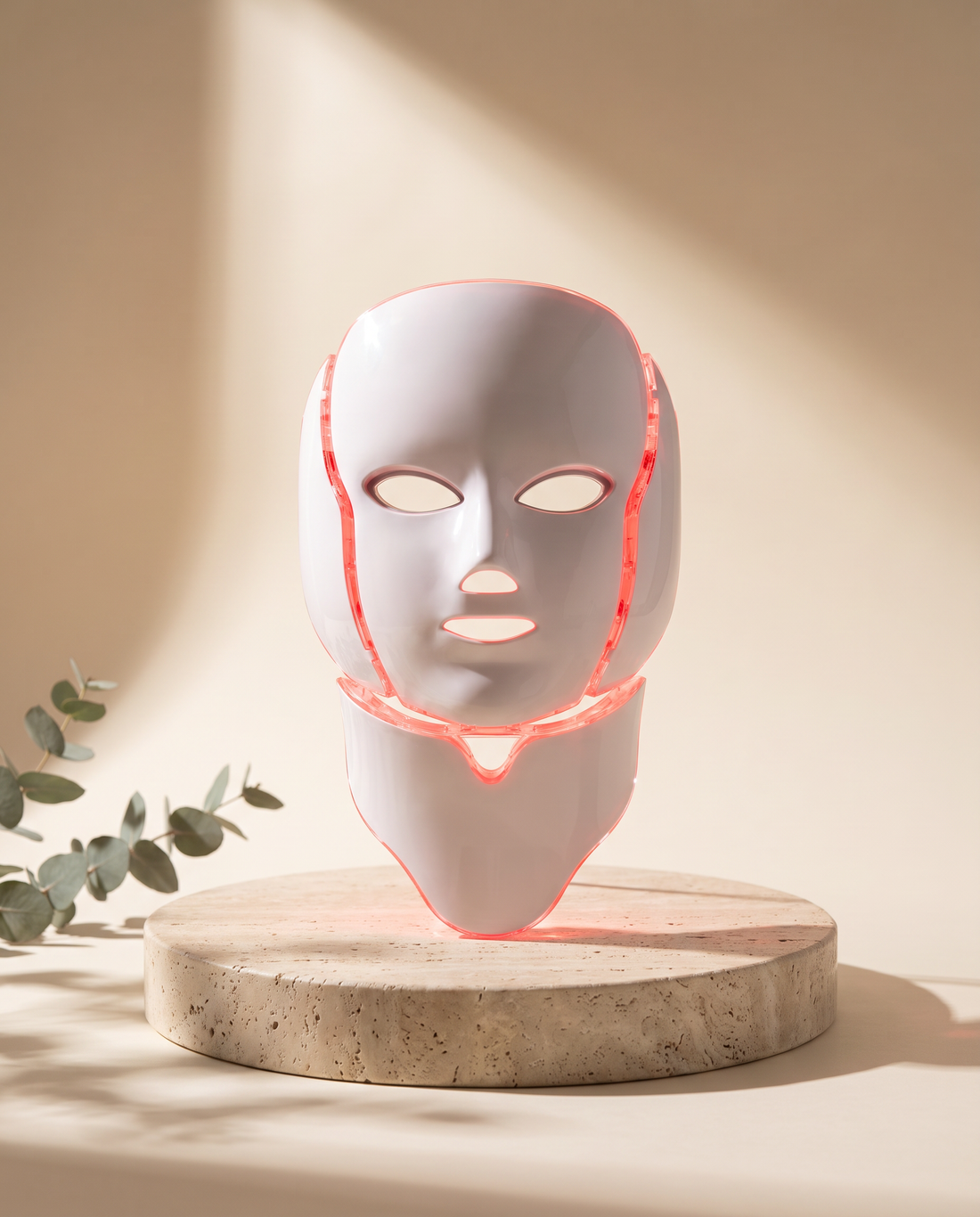 Photon LED mask with neck panel on a travertine pedestal, red light mode